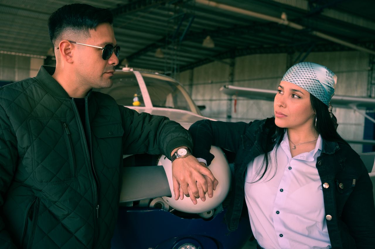 Two adults having a casual conversation in an airplane hangar.